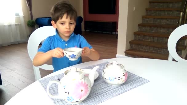 Küçük Bir Çocuk Masada Oturur Fincandan Çay Içer — Stok video