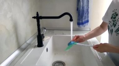 Mutfaktaki kız kirli çatal bıçak takımlarını bir su deresinin altında yıkıyor..