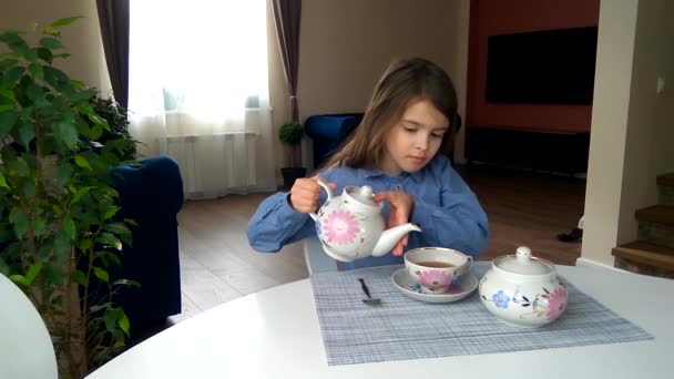 女孩坐在桌旁 用杯子倒茶和喝茶 — 图库视频影像