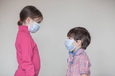 Coronavirus salgını sırasında tıbbi maske takmış iki kardeş.