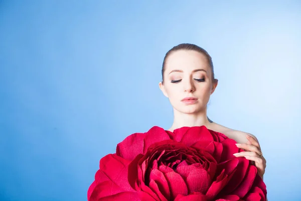 Sağlıklı ciltli güzel bir kız, kırmızı çiçekli bir spa tedavisinden sonra rahatlar.