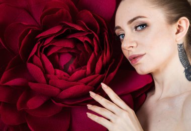 Sağlıklı ciltli güzel bir kız, kırmızı çiçekli bir spa tedavisinden sonra rahatlar.