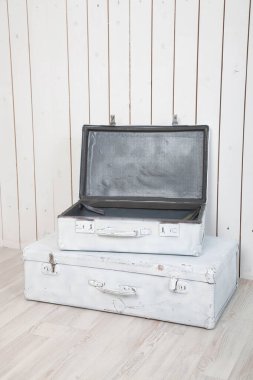 Beyaz tahta bir duvara karşı iki antika beyaz bavul.