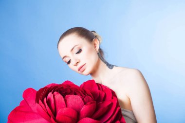 Sağlıklı ciltli güzel bir kız, kırmızı çiçekli bir spa tedavisinden sonra rahatlar.