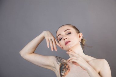 Dövmeleri ve kaplıca ve kozmetik ürünlerinden sonra yumuşak bir cildi olan genç ve güzel bir model. 