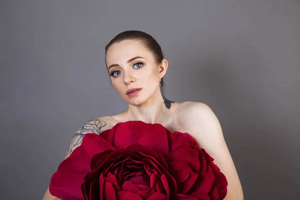 beautiful young model with tattoos and soft skin after Spa treatments and cosmetics with a red rose
