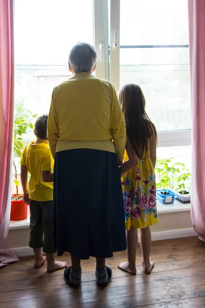 Babcia Wnuki Stoją Przy Dużym Oknie Patrzą Ulicę — Zdjęcie stockowe