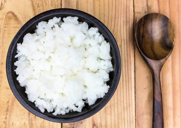 Reis in eine Tasse auf einen Holztisch legen. — Stockfoto
