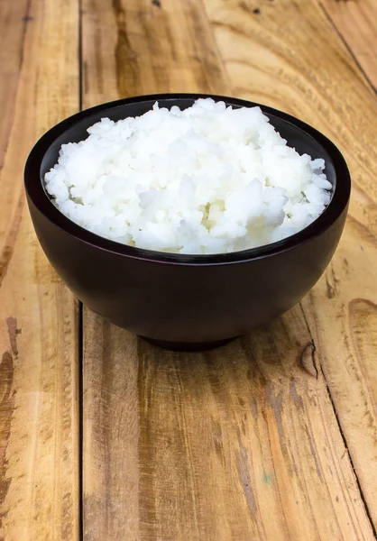 Colocar el arroz en una taza sobre una mesa de madera . — Foto de Stock