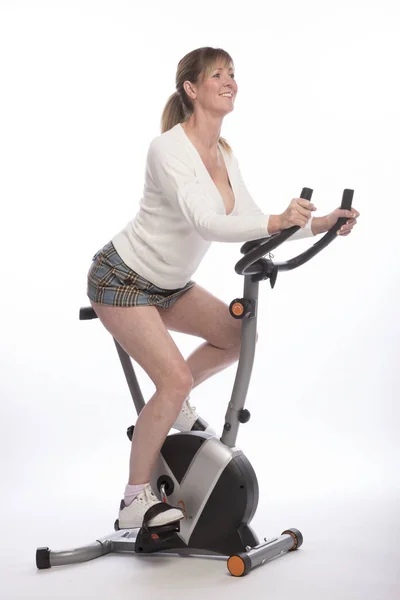 Woman exercising on an exercise bicycle — Stock Photo, Image