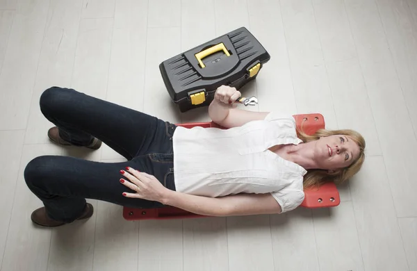 Vrouw met een werkset en spanner opleggen van een trolley — Stockfoto