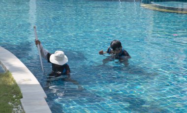 Otel çalışanları bir yüzme havuzu temizlemeye. Tayland 2014