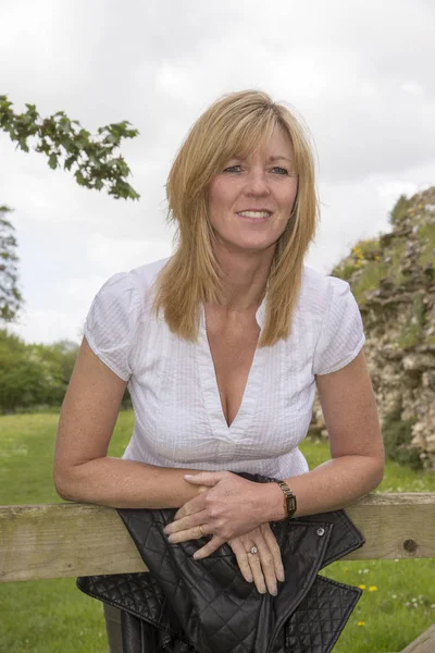 Orta yaşlı sarışın kadın ahşap kapıya yaslanmış