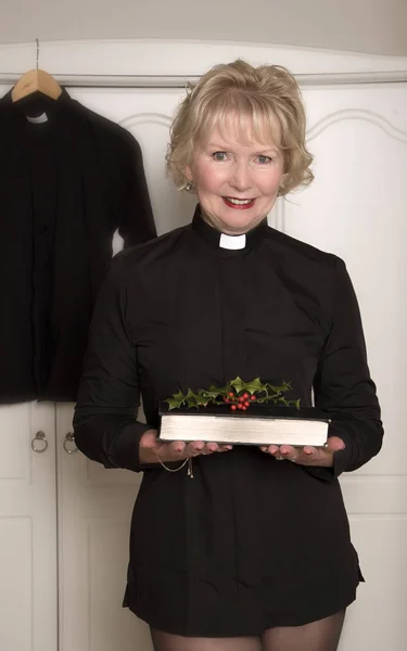 Religious woman in black holding a sprig of Holly and a book — Stock Photo, Image