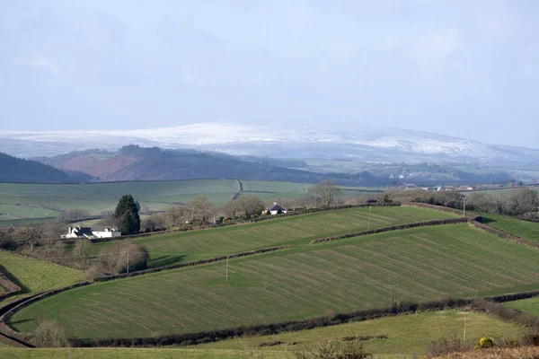 Сільськогосподарських угідь і далеких сніг покриті пагорби в Девоні Англії Великобританії — стокове фото