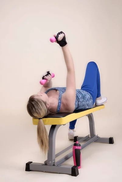 Woman on a weightlifting bench in a gym using weights — Stock Photo, Image