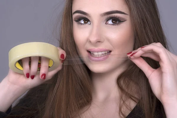 Mujer con un rollo de cinta adhesiva arrancando una longitud del rollo — Foto de Stock