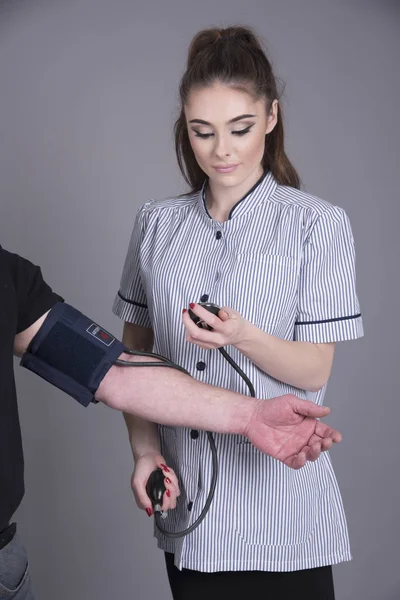 Sestra v jednotné odběr krevního tlaku — Stock fotografie