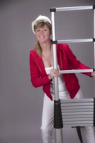 Una trabajadora en su lugar de trabajo usando una escalera —  Fotos de Stock
