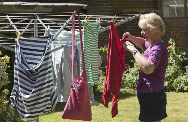 Äldre kvinna hänger tvätt ut att torka — Stockfoto
