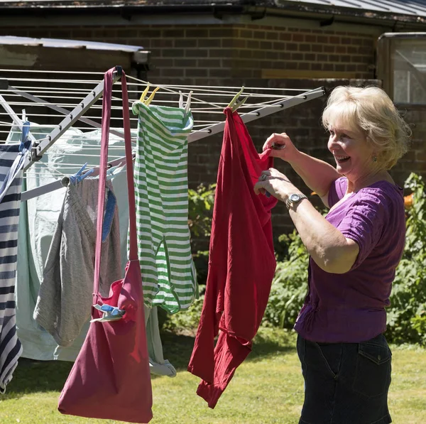 Äldre kvinna hänger tvätt ut att torka — Stockfoto