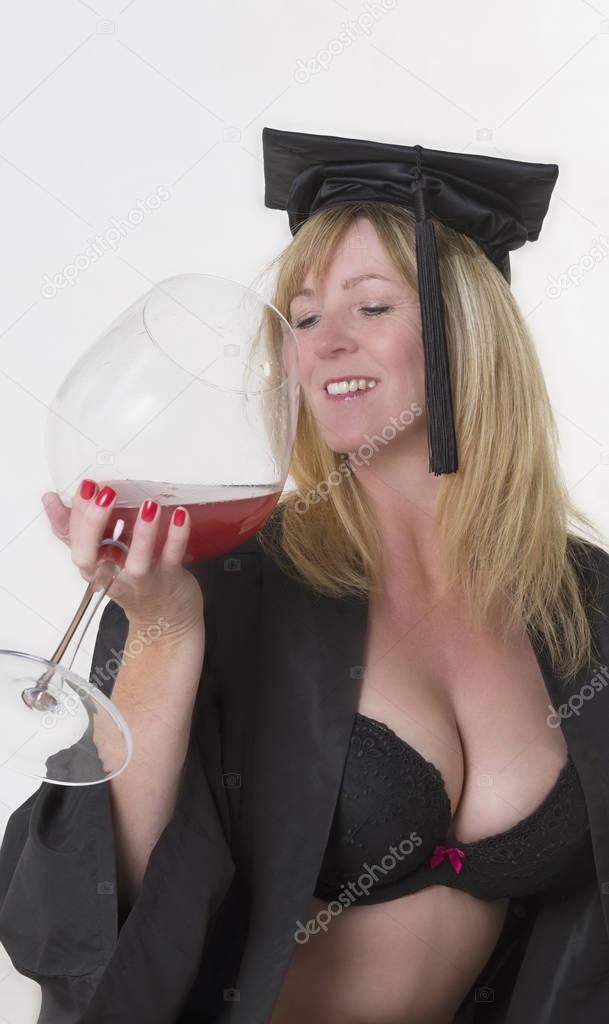 Mature student wearing a hat with gown and holding a glass of wine