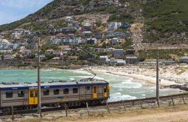 Glencairn, Cape Town, South Africa. December 2019. Coastal passenger train passing the resort of Glencairn on the coast to Simons Town where it terminates. clipart