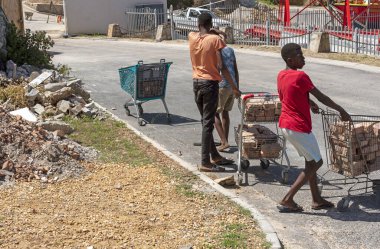 Zwelihle, Hermanus, Batı Burnu, Güney Afrika. Aralık 2019. Gençler, Hermanus, Batı Cape, Güney Afrika 'daki Zwelihle kasabasında yol kenarındaki alışveriş arabalarında eski tuğlaları topluyor..