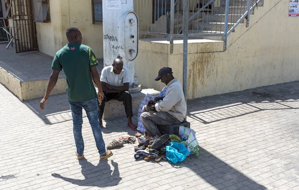 Zwelihle, Hermanus, Batı Burnu, Güney Afrika. Aralık 2019. Hermanus, Batı Burnu, Güney Afrika 'daki Zwelihle kasabasının yol kenarında ayakkabıları tamir eden ve temizleyen adam..