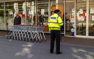 Winchester, Hampshire, İngiltere, Mart 2020. Winchester süpermarketinin önünde güvenlik görevlisi. Coronavirus salgını sırasında tek bir müşteriye izin veriliyor..