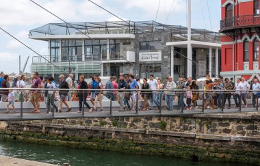 Cape Town, Güney Afrika. 2019. V & A Rıhtım Ziyaretçileri Cape Town 'daki liman girişi üzerinden salıncak köprüsünden geçiyorlar.