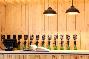 Bardaki büyük eşzamanlı dökülüp bira. Ahşap bar. Bir kitap, bir kasa bira, bir lamba ile ahşap masa. Bira Festivali. Bira Festivali. Özel bira bar.