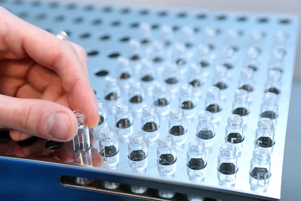 Les personnes tenant à la main un ensemble de flacons de tube à essai pour analyse dans le chromatographe liquide en phase gazeuse. Assistant de laboratoire insérant une bouteille en verre de laboratoire dans un flacon chromatographique — Photo