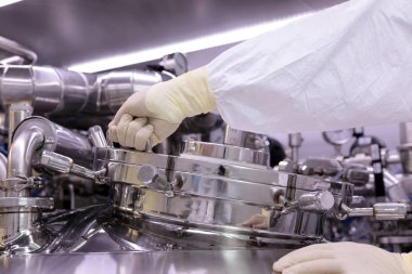 İlaç üretimi için büyük bir rektör. Adam reaktör kapak kapatır. Süspansiyon ekstresinin hazırlanması. İlaç fabrikası reaktör. Tıbbi sanayi.