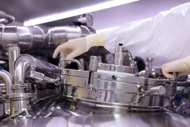 İlaç üretimi için büyük bir rektör. Adam reaktör kapak kapatır. Süspansiyon ekstresinin hazırlanması. İlaç fabrikası reaktör. Tıbbi sanayi.