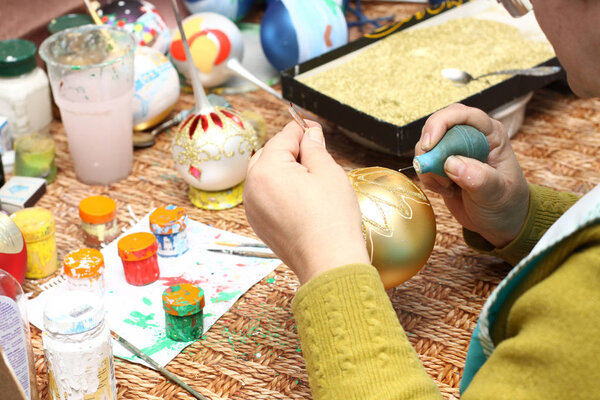 Factory of Christmas toys. The worker blows out the glass. The burner melts the glass. Decoration of a Christmas tree toy. Handmade. Manufacture of fur-tree toys. Many beautiful glass beads. Burning products in the oven.