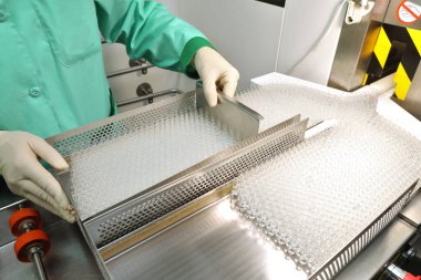 Tıpla ampullerin görsel kontrolü. Bir kadın ampul üretim bandında çalışıyor. Steril şişeler ve ampuller dağıtım hattında. İlaç ile mühürlenmiş ampuller. Steril kapsüller
