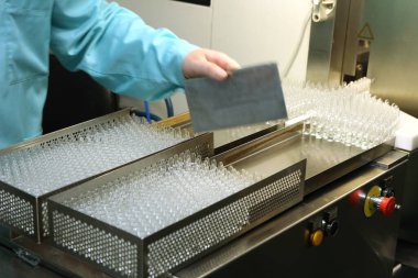 Tıpla ampullerin görsel kontrolü. Bir kadın ampul üretim bandında çalışıyor. Steril şişeler ve ampuller dağıtım hattında. İlaç ile mühürlenmiş ampuller. Steril kapsüller