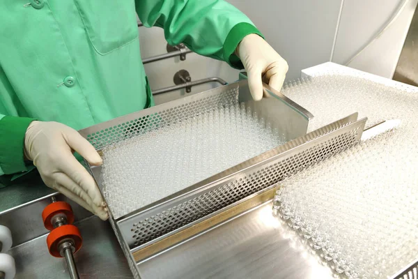 Control visual de ampollas con medicamentos. Una mujer trabaja en una línea de producción de ampollas. Frascos y ampollas estériles en la línea dispensadora. Ampollas selladas con medicina. Cápsulas estériles para —  Fotos de Stock