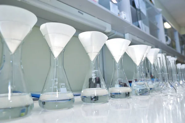 Durchführung eines chemischen Experiments in einem Labor. Farbige Kolben mit chemischen Reagenzien. Viele medizinische Glasflaschen in den Händen eines Wissenschaftlers. Schöne Farbreagenzienlösung. Gelber und brauner Test — Stockfoto