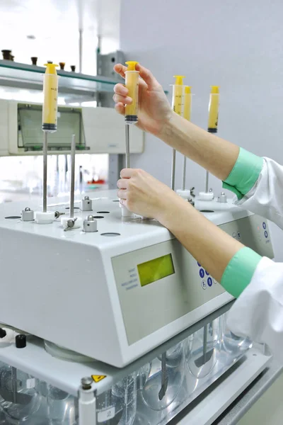 Um químico fêmea realiza testes de solubilidade de comprimidos e outras formas de dosagem. Erveka - Laboratório farmacêutico de pesquisa científica. Um homem realiza um trabalho científico numa fábrica. Investigação laboratorial . — Fotografia de Stock