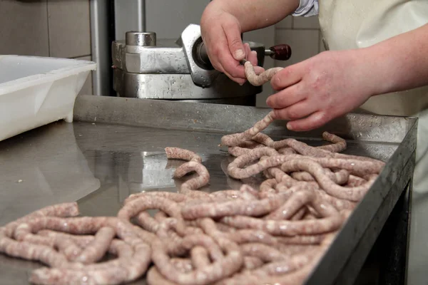 Prepares sausages at the work table. Food processing and processing industry. Raw meat mix: steaks, poultry, sausages, ham, chopped, minced meat. The farm. Unique home production.