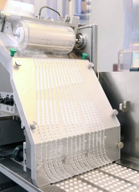 Kapsül ilaç üretim hattı, endüstriyel ilaç konsepti. Makineden tabletler çıkıyor. Eczane ilaç üretim taşıyıcısı. Hap üretimi. Kabaran taşıyıcı