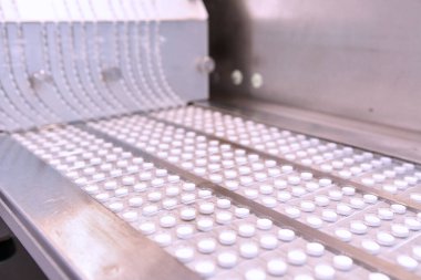 Kapsül ilaç üretim hattı, endüstriyel ilaç konsepti. Makineden tabletler çıkıyor. Eczane ilaç üretim taşıyıcısı. Hap üretimi. Kabaran taşıyıcı