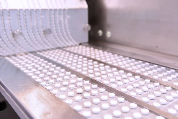 Capsule medicine pill production line, Industrial pharmaceutical concept. Tablets coming out of the machine. Pharmacy medicine pill production conveyor. Tablet pill production. Blistering conveyer