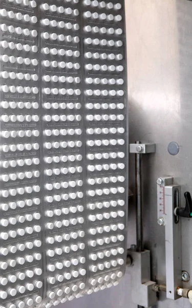 Capsule medicine pill production line, Industrial pharmaceutical concept. Tablets coming out of the machine. Pharmacy medicine pill production conveyor. Tablet pill production. Blistering conveyer