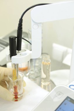 Bir kimyager çözeltinin sertliğini araştırır. Laboratuvar PH ölçümü. PH 'ı kimyasal olarak ölçmek için bir cihaz. İlaç üretimi için modern ekipman. Bir bilim adamı bir deney yapıyor..