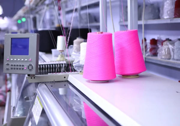 縫製工場を背景に糸のピンクのスプール。衣類産業。繊維産業のための機械。衣料品の製造。仕立てのための新工場. — ストック写真