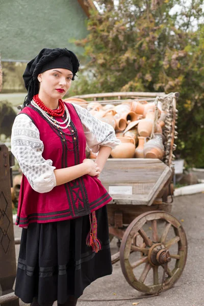 Piękna dziewczyna w sukience narodowej. Trzyma w rękach starożytny garnek. Starożytna odzież z końca XIX wieku. Piękna sukienka i spódnica na kobiecie. Koncepcja życia na wsi, tradycje narodowe — Zdjęcie stockowe