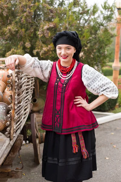 Beautiful girl in national dress. Holding an ancient pot in his hands. Antique clothing of the late 19th century. Beautiful dress and skirt on a woman. The concept of rural life, national traditions — Stock Photo, Image